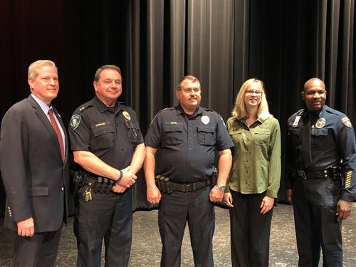 Group of police officers and others standing on stage 